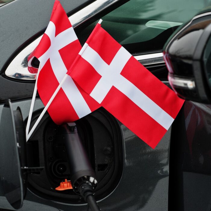 Denmark flag ecological car concept. Plugging a power supplier, charging modern automobile.