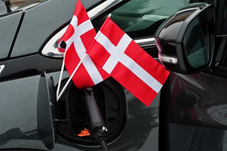 Denmark flag ecological car concept. Plugging a power supplier, charging modern automobile.